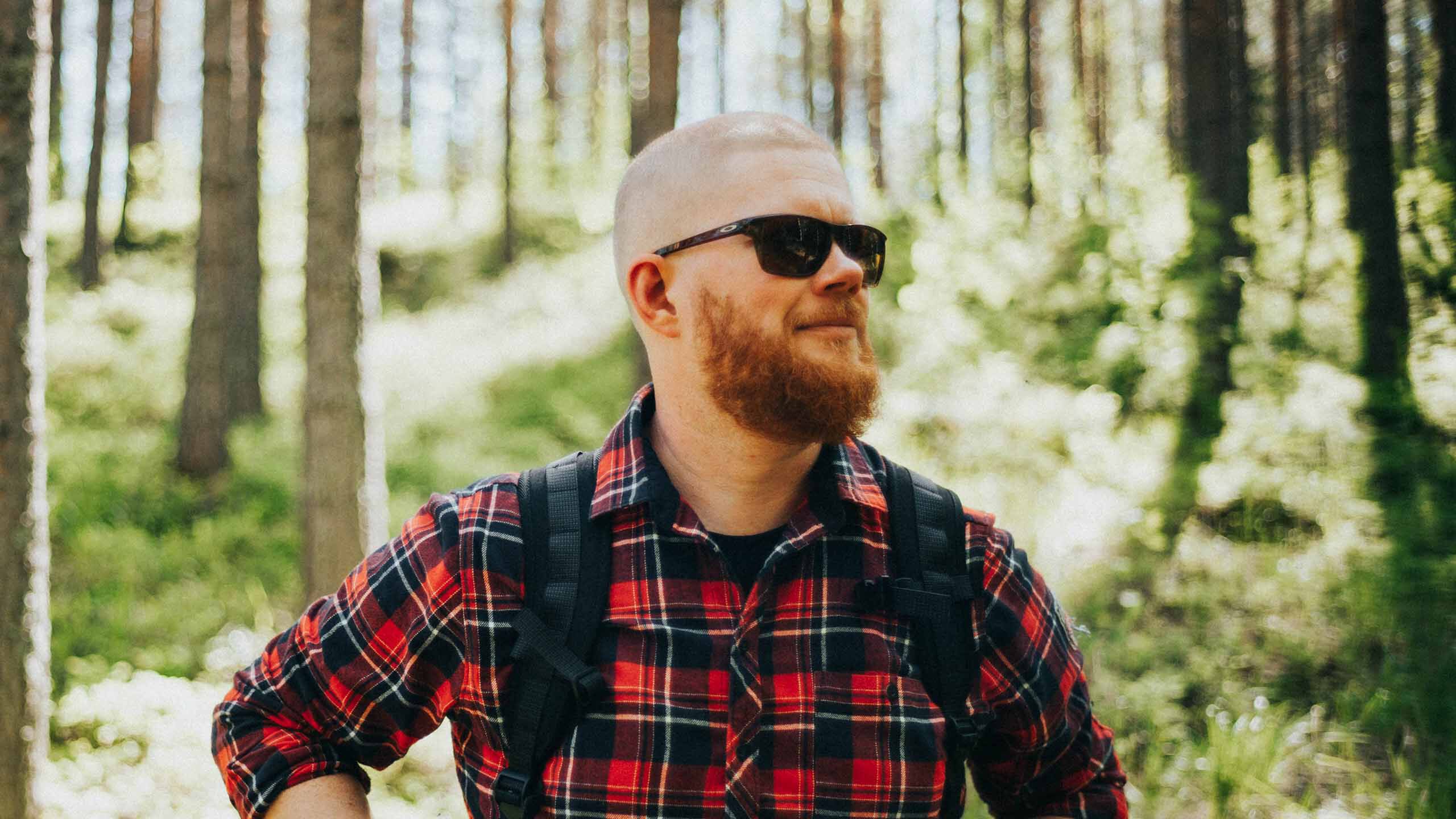 Mies vaelluksella mets&auml;ss&auml; aurinkolasit p&auml;&auml;ss&auml;.